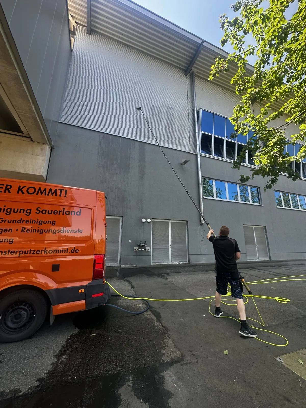 Reinigung einer Metallfassade, im Vordergrund der Firmenwagen