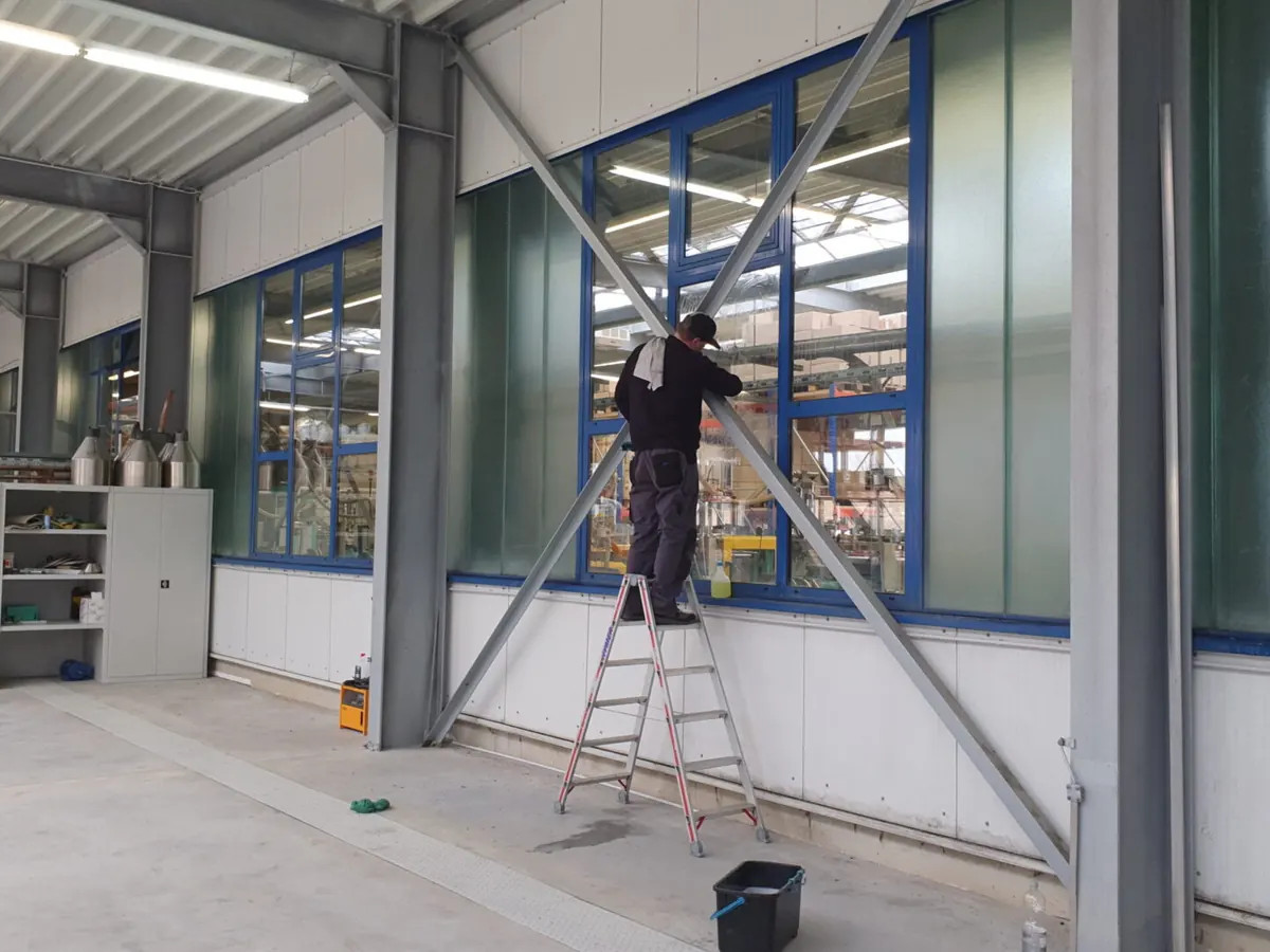 Glasreinigung an einer Fensterfront in einer Betriebshalle