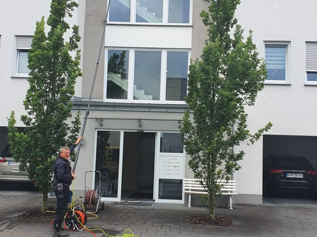 Treppenhausfenster eines Mehrfamilienhauses werden mit der Stange gereinigt