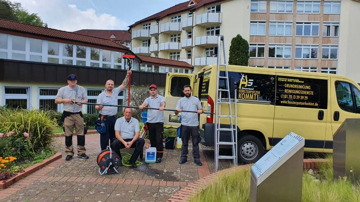 Das Team der Gebäudereinigung Sauerland mit Arbeitsgeräten vor den Firmenwagen