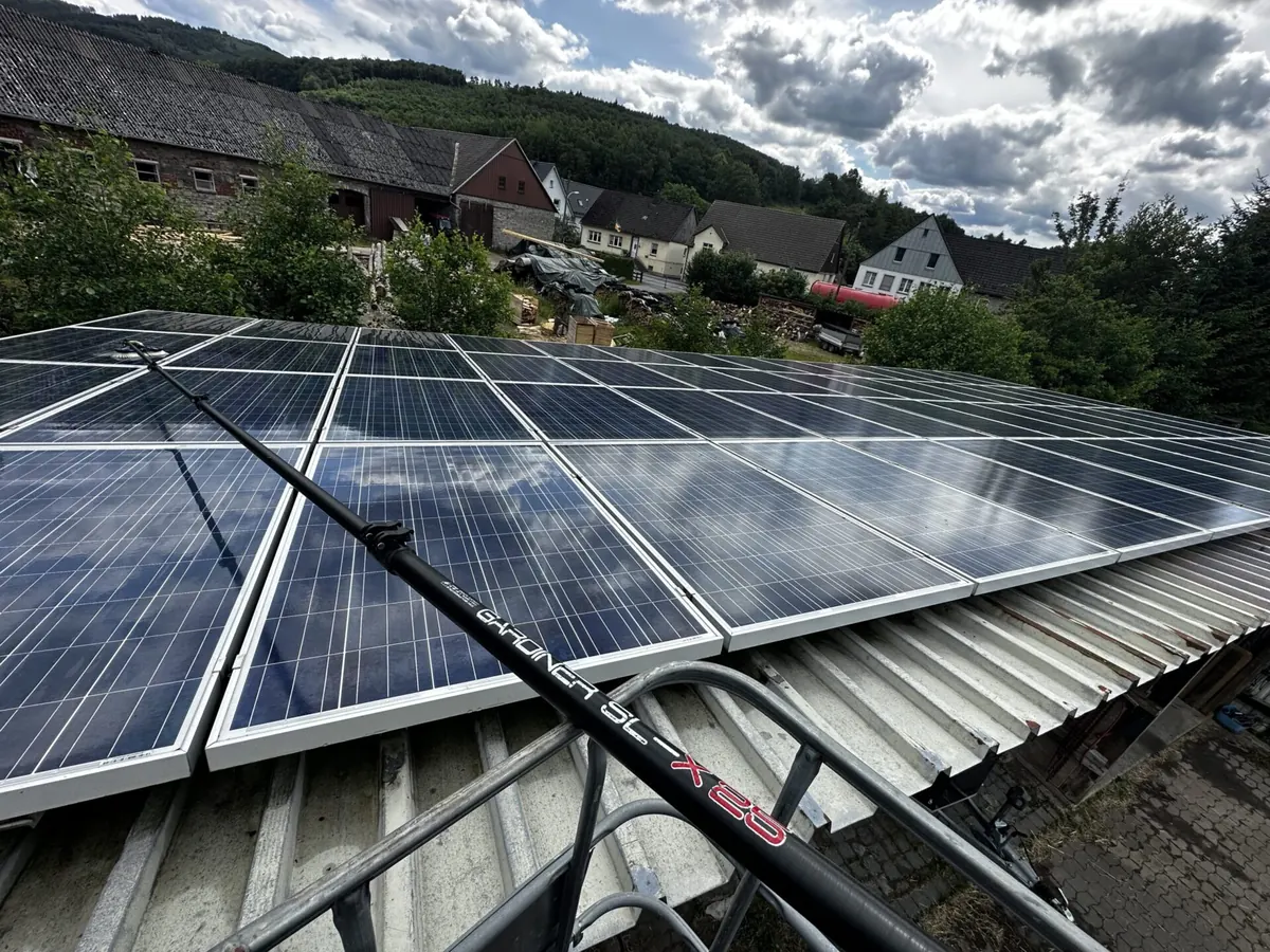 Nahaufnahme: Reinigungsbürste an einer Carbonstange auf Solarmodulen