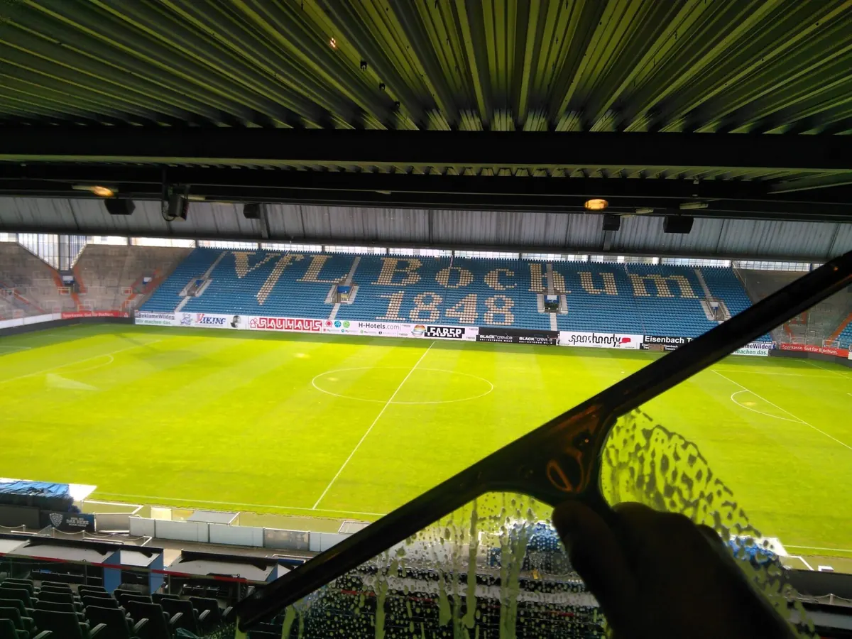 Blick durch eine frisch gereinigte Glasscheibe auf das Spielfeld des Stadions in Bochum