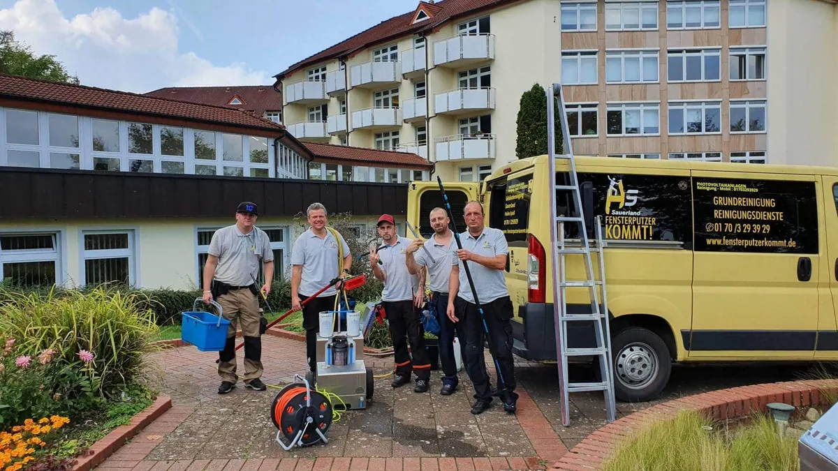 Das Team der Gebäudereinigung Sauerland vor den Firmenfahrzeugen