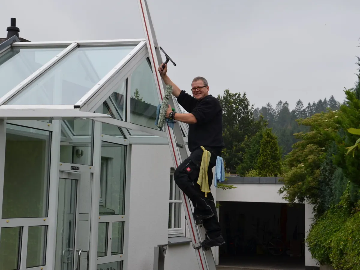 Reinigung eines Wintergartens mit Leiter und Teleskopstange